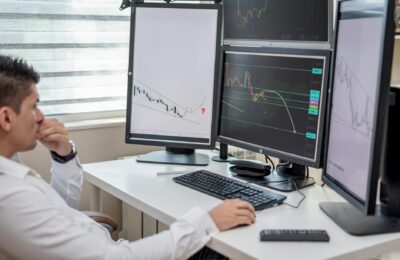 Financial analyst studying gold price charts on multiple screens during April 2026 market volatility