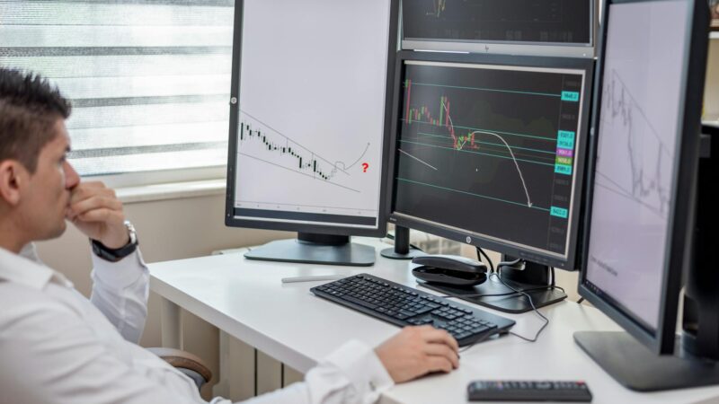 Financial analyst studying gold price charts on multiple screens during April 2026 market volatility