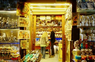 Egyptian customers examining gold jewelry at a busy Cairo gold market shop with display cases of 21-karat pieces