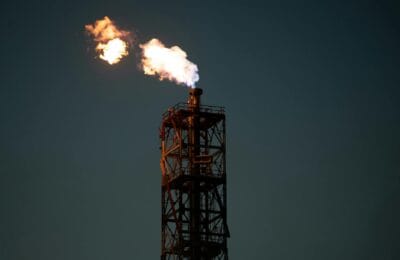 Gulf oil refinery under attack with smoke rising, illustrating the 2026 drone strike crisis on energy infrastructure