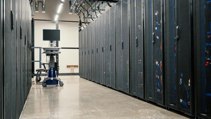 Data center server room with security monitoring screens representing tech infrastructure under threat