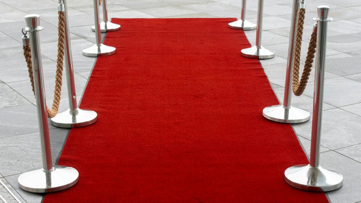 Film festival red carpet ceremony at night with golden award statues and dramatic lighting, representing the intersection of Iranian cinema excellence and global recognition at the Oscars 2026 | حفل سجادة حمراء في مهرجان سينمائي ليلاً مع تماثيل جوائز ذهبية وإضاءة درامية، تمثل تقاطع التميز السينمائي الإيراني والاعتراف العالمي في الأوسكار 2026