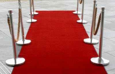 Film festival red carpet ceremony at night with golden award statues and dramatic lighting, representing the intersection of Iranian cinema excellence and global recognition at the Oscars 2026 | حفل سجادة حمراء في مهرجان سينمائي ليلاً مع تماثيل جوائز ذهبية وإضاءة درامية، تمثل تقاطع التميز السينمائي الإيراني والاعتراف العالمي في الأوسكار 2026