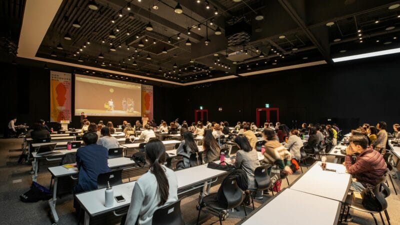 OPEC+ ministers and delegates seated around a conference table at an oil production meeting with national flags in background