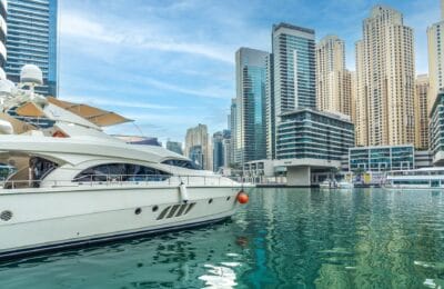 Luxury yacht docked at Dubai Marina with illuminated skyscrapers reflecting wealth and lifestyle