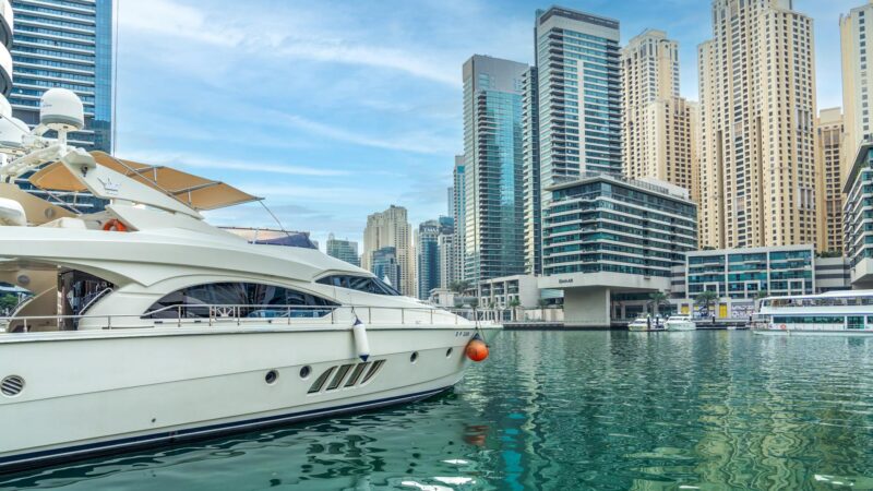 Luxury yacht docked at Dubai Marina with illuminated skyscrapers reflecting wealth and lifestyle