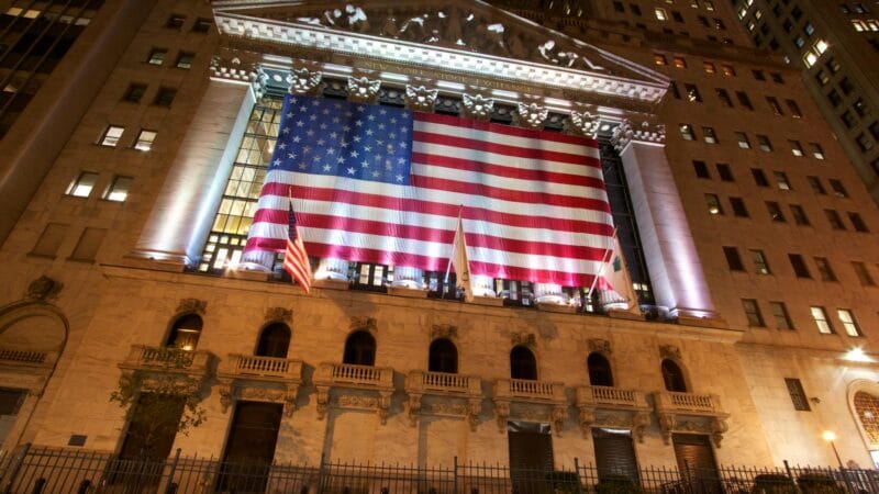 New York Stock Exchange building with American flags on Wall Street - بورصة نيويورك وول ستريت بعد وقف إطلاق النار مع إيران
