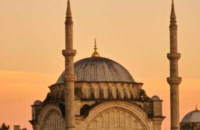 Tourists visiting a historic mosque in Istanbul Turkey at sunset with the city skyline in the background