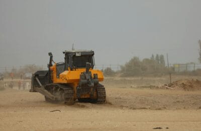 Large construction site in the desert with heavy machinery and equipment surrounded by sand dunes showing a mega-project under development