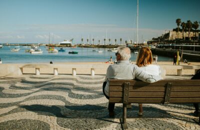 Relaxed elderly expat couple walking along a Mediterranean beach at sunset