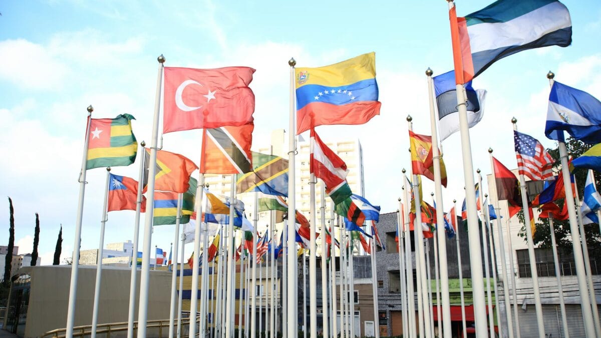 Heads of state gathered around a circular table at a BRICS leaders' summit, flags of member nations displayed behind them in a modern conference hall