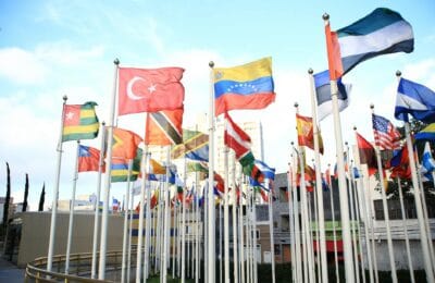Heads of state gathered around a circular table at a BRICS leaders' summit, flags of member nations displayed behind them in a modern conference hall