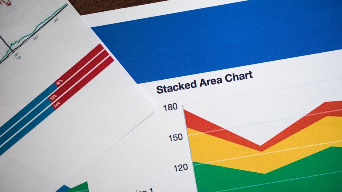 Stacked gold bars inside a vault with an analytical price chart projected behind