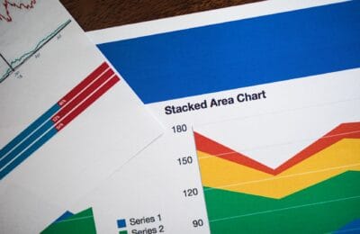 Stacked gold bars inside a vault with an analytical price chart projected behind