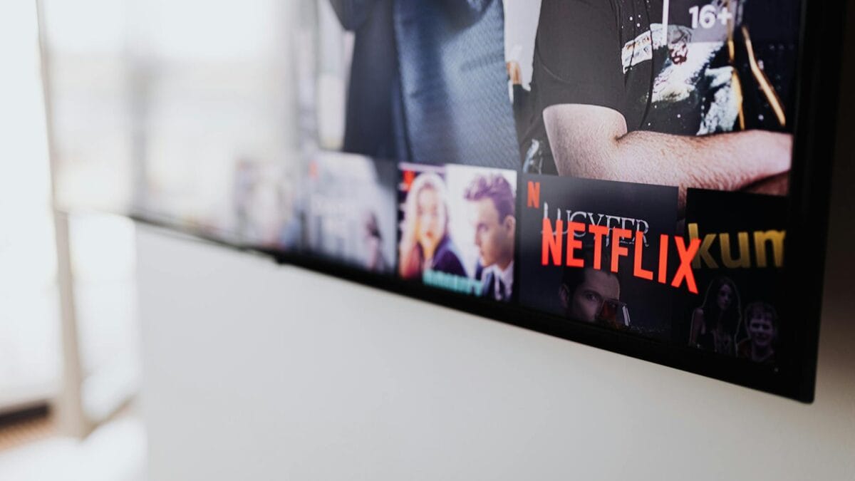 An American flag draped behind a large television displaying streaming service logos in a home setting
