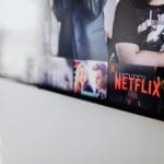 An American flag draped behind a large television displaying streaming service logos in a home setting