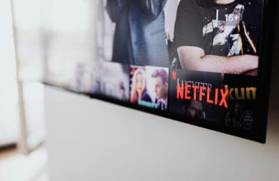 An American flag draped behind a large television displaying streaming service logos in a home setting