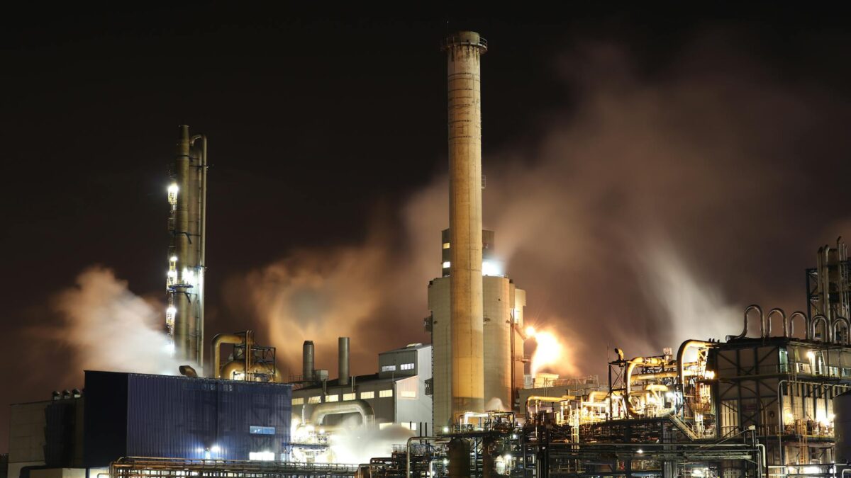 Damaged Gulf oil refinery at night with smoke and emergency flares