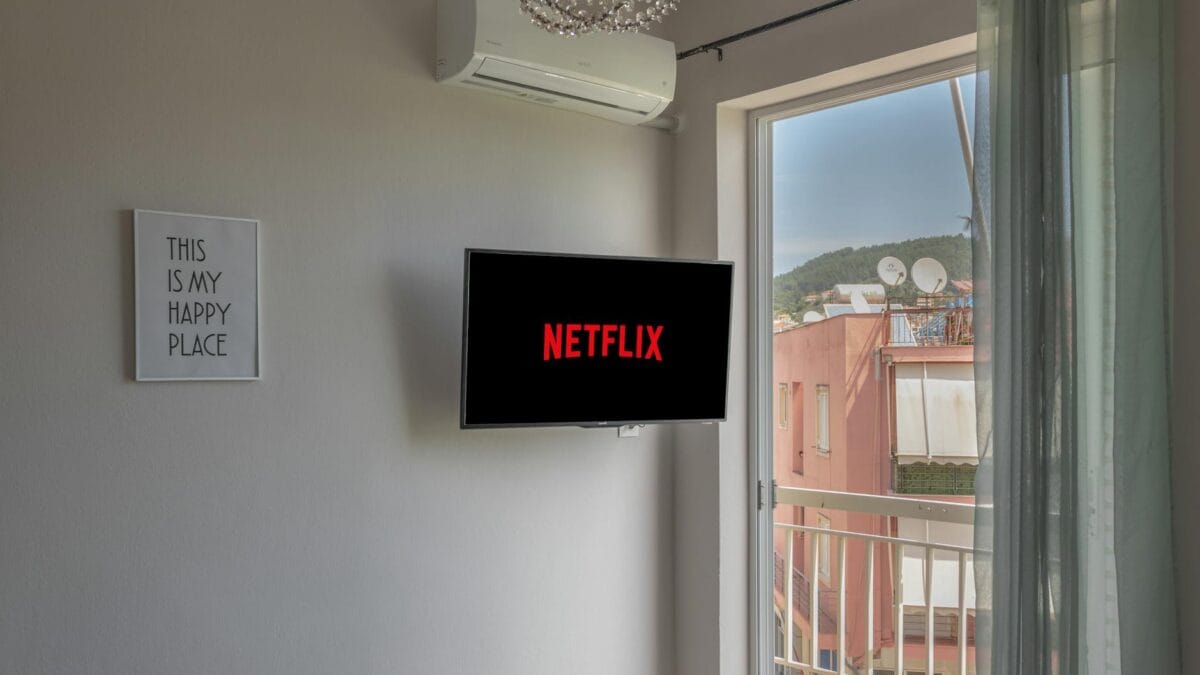 A large television screen displaying the Netflix red logo in a home entertainment setup with ambient lighting