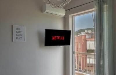 A large television screen displaying the Netflix red logo in a home entertainment setup with ambient lighting