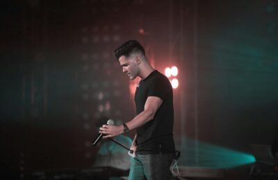 Egyptian male superstar performing on a brightly lit concert stage with smoke and lights