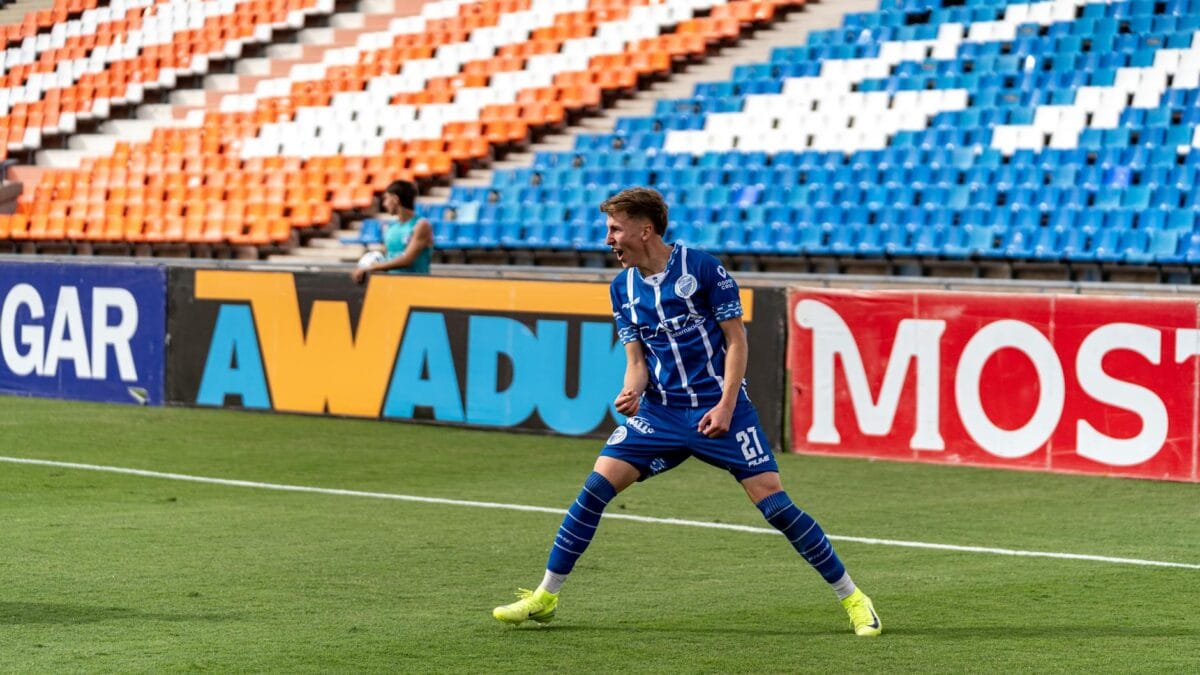 A professional footballer celebrating a goal in front of cheering stadium fans