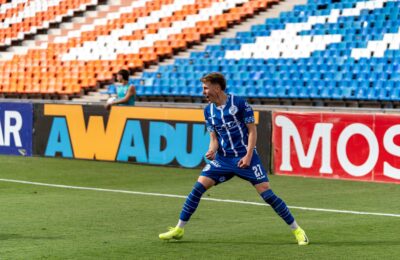 A professional footballer celebrating a goal in front of cheering stadium fans