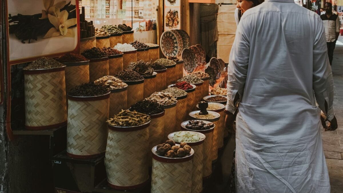 Tourist couple walking through a traditional Arab souq market exploring spices and textiles