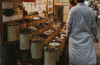 Tourist couple walking through a traditional Arab souq market exploring spices and textiles